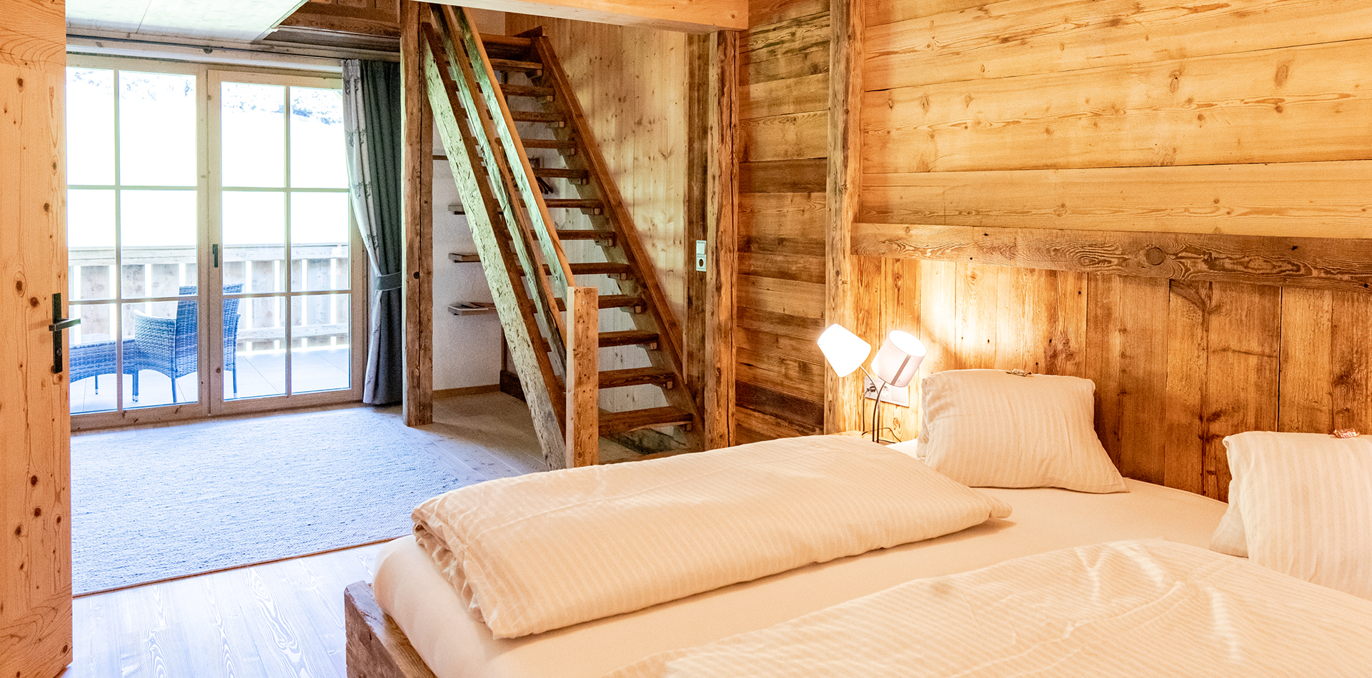 berggasthof-steckholzer-familienzimmer-doppelbett-mit-blick-auf-balkon-und-treppenaufgang © Tourismusverband Wipptal / Helena Beeremeister